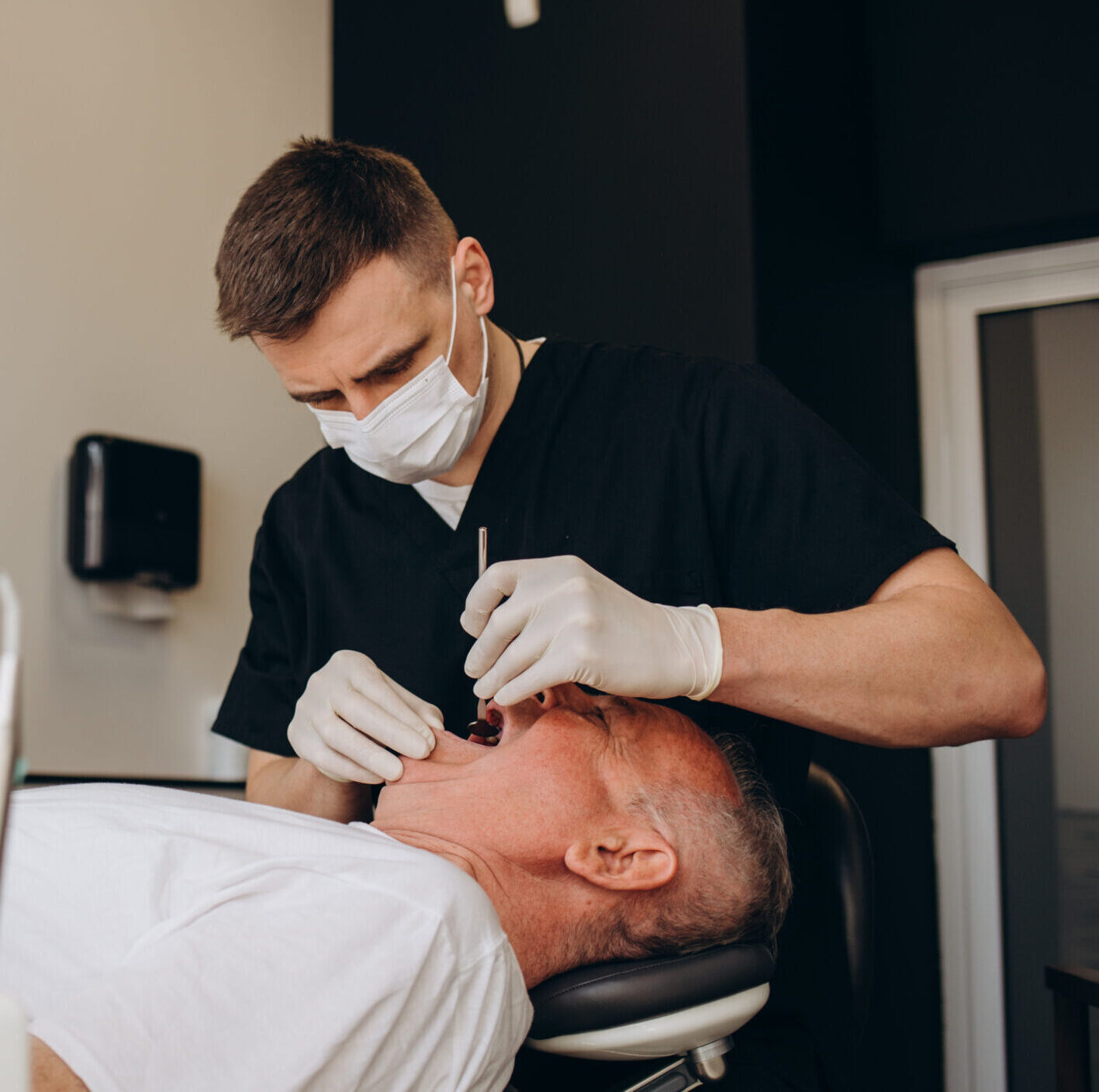 Handsome old man talking to the dentist. Female doctor and senior man in the dentist's office. Grandfather looking into the mirror on his teeth.