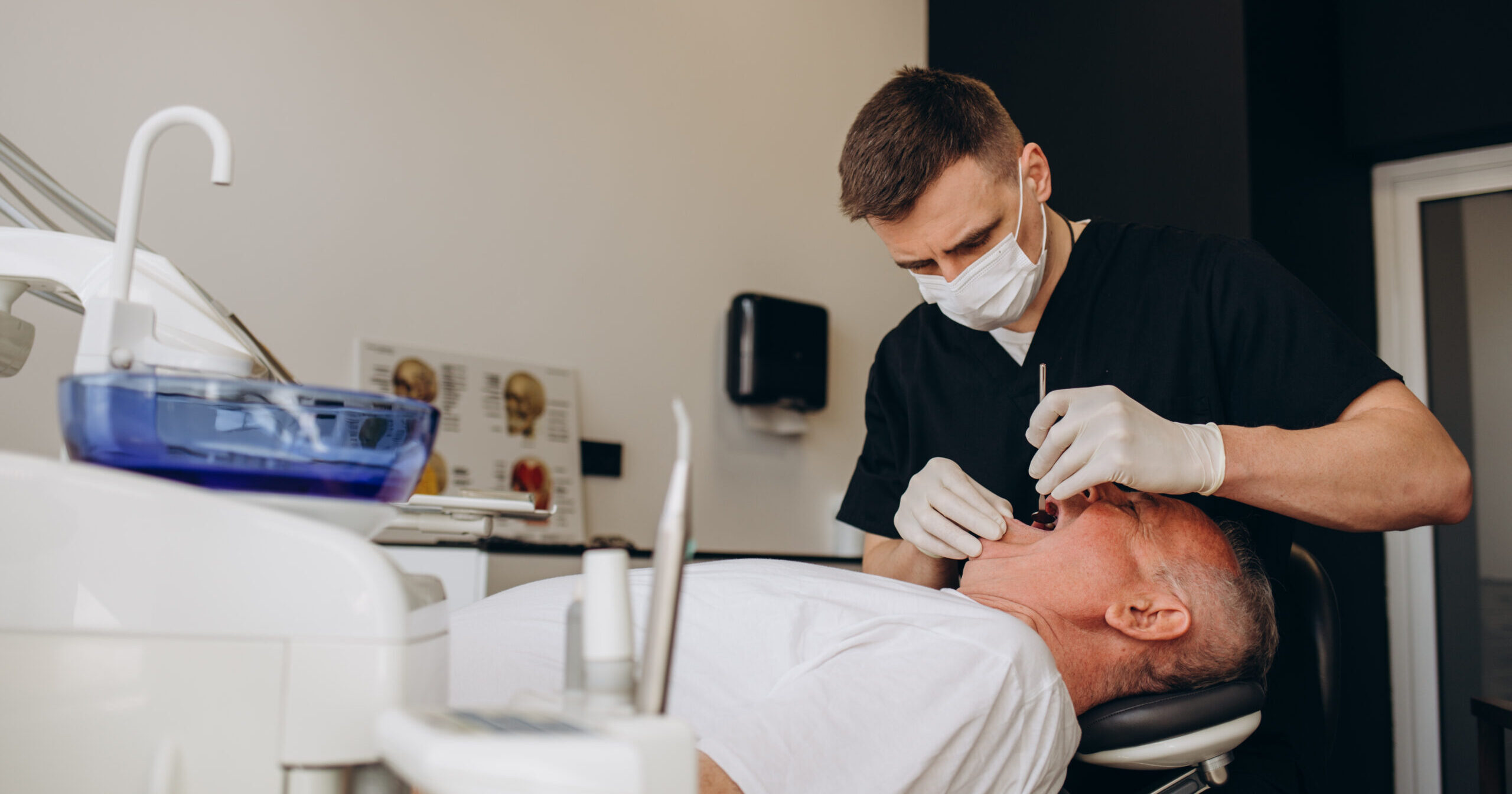 Handsome old man talking to the dentist. Female doctor and senior man in the dentist's office. Grandfather looking into the mirror on his teeth.